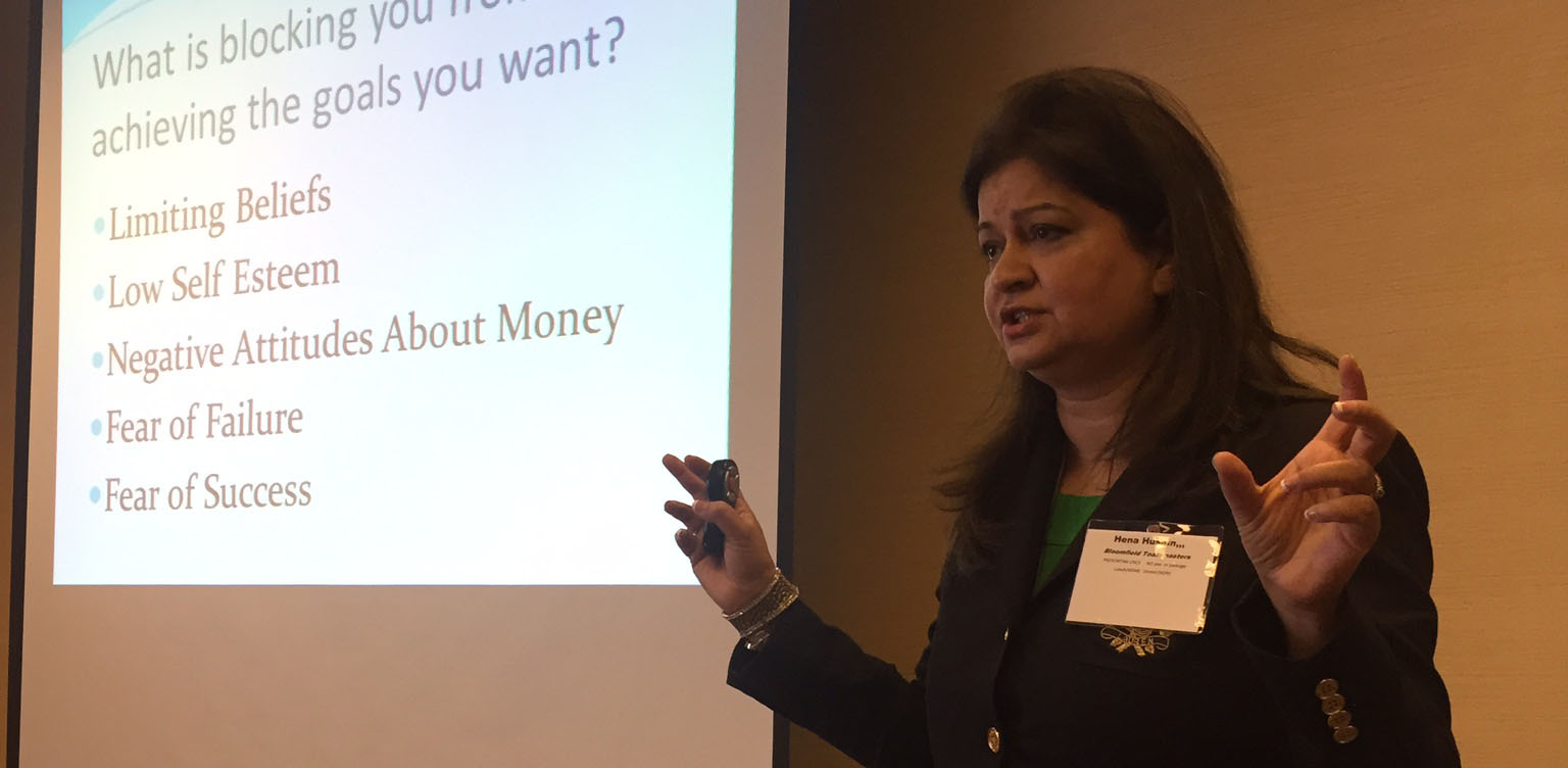 Hena presenting beside a slide on limiting beliefs and success