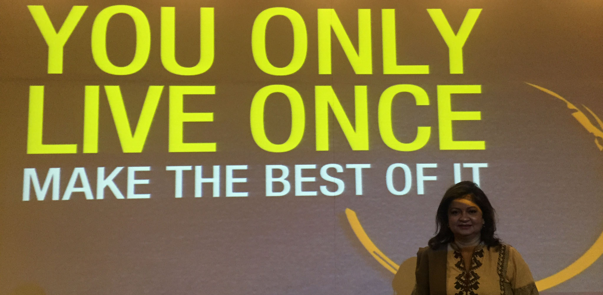 Hena standing in front of a You Only Live Once presentation screen